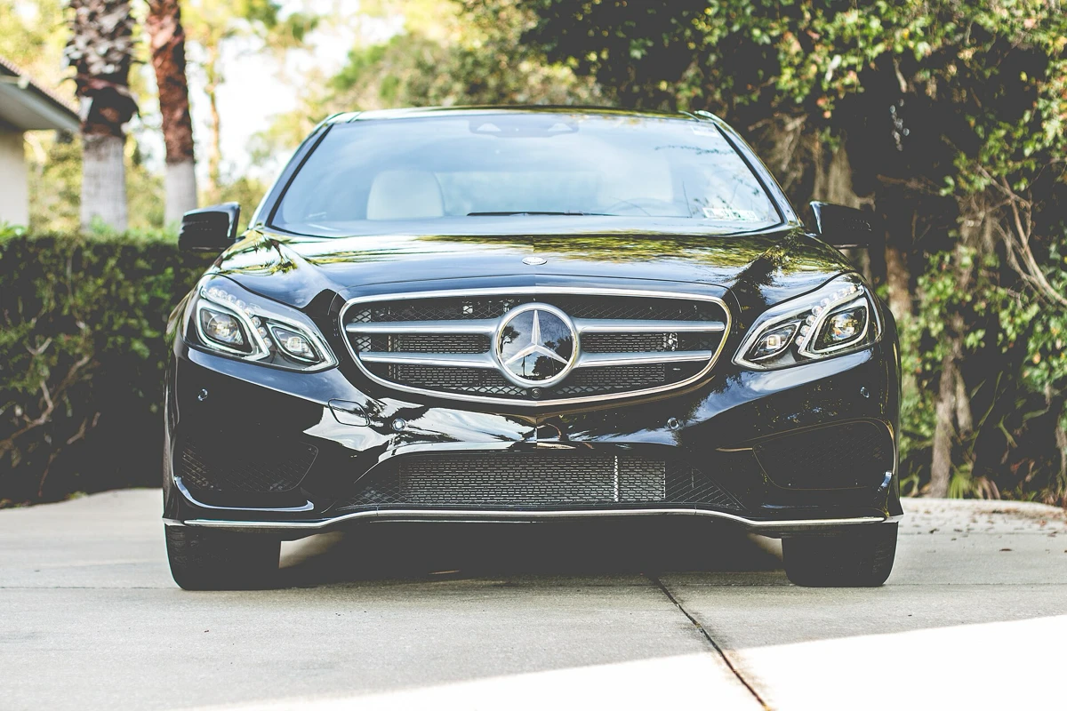 Black executive saloon parked under trees