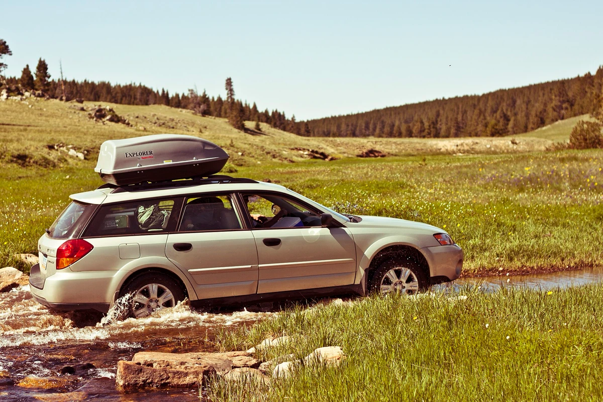 Estate car with a roof box parked in a mountain meadow
